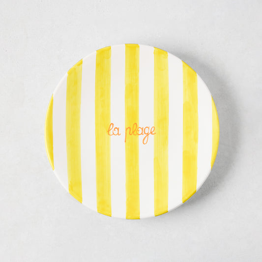 Hand-painted ceramic appetizer plate with bright yellow stripes and orange "la plage" text.