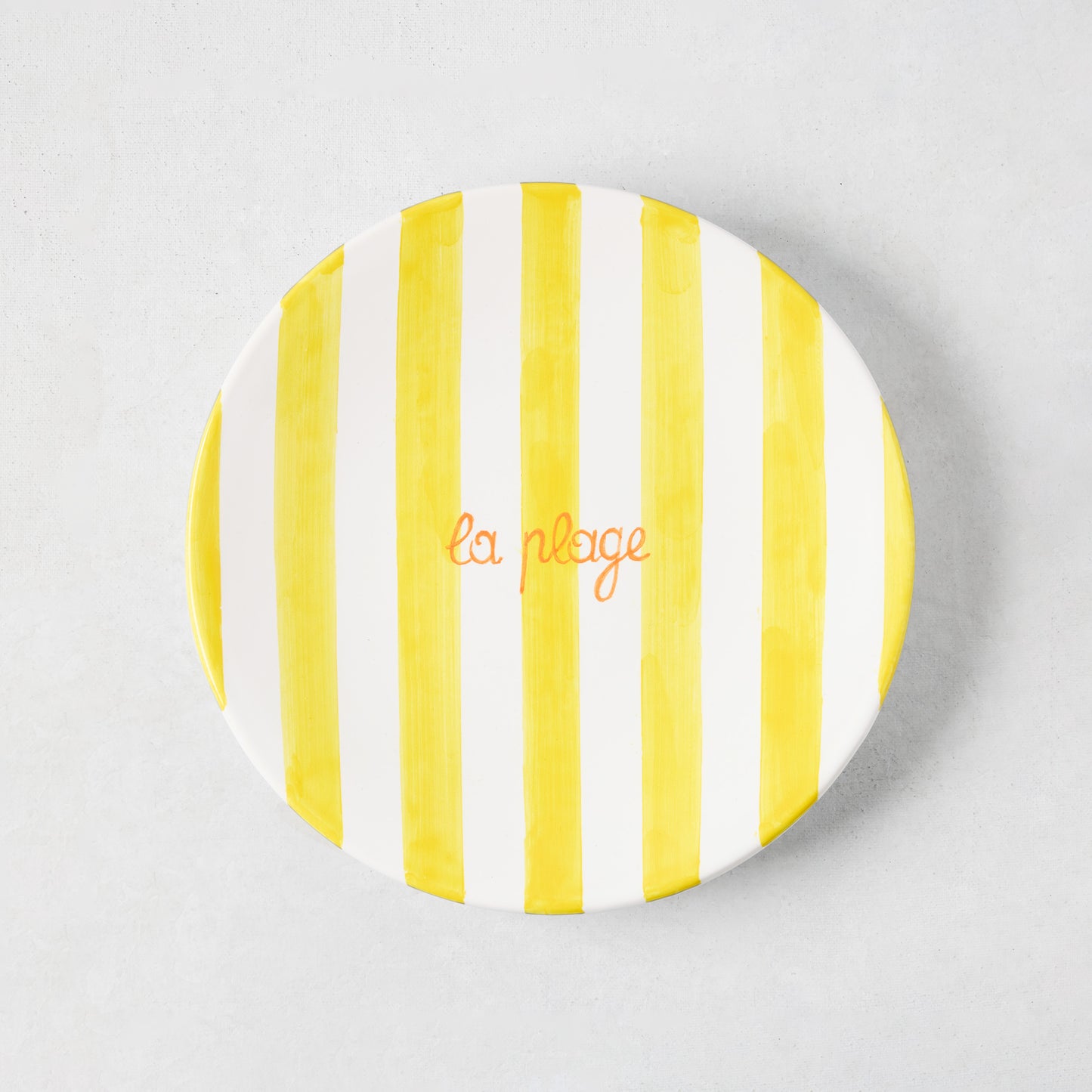 Hand-painted ceramic appetizer plate with bright yellow stripes and orange "la plage" text.