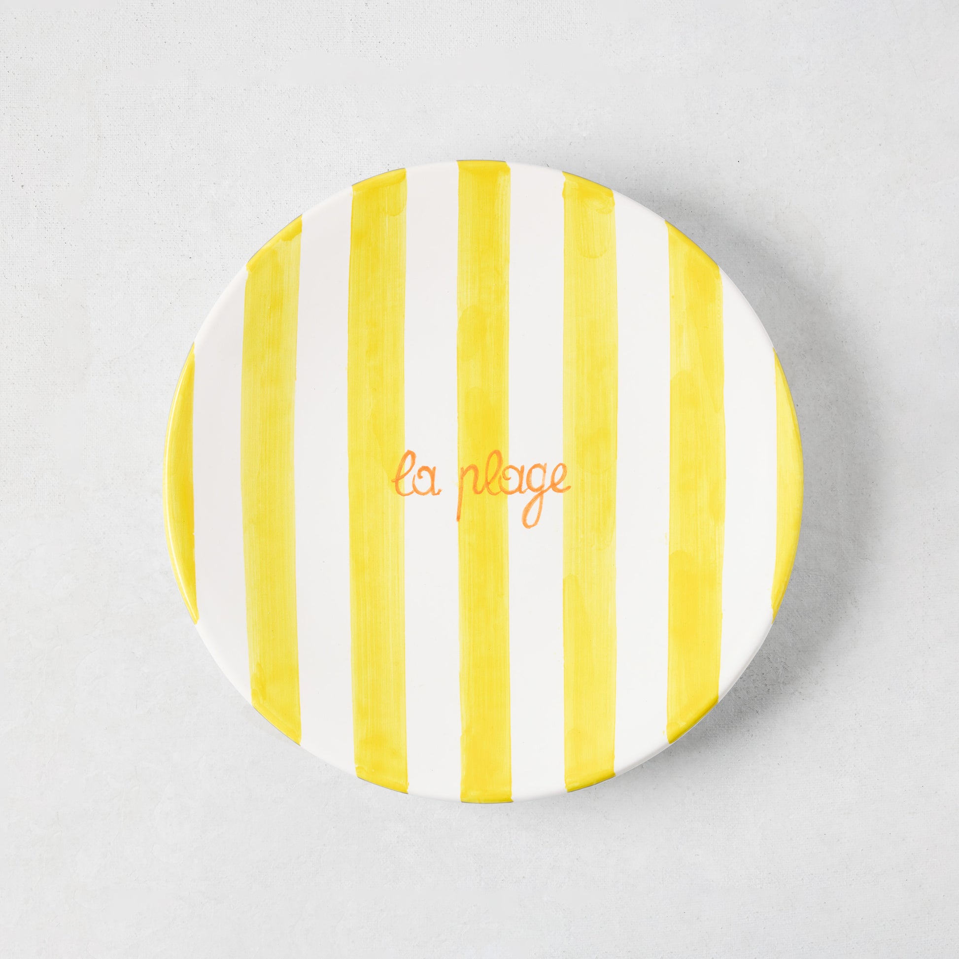 Hand-painted ceramic appetizer plate with bright yellow stripes and orange "la plage" text.
