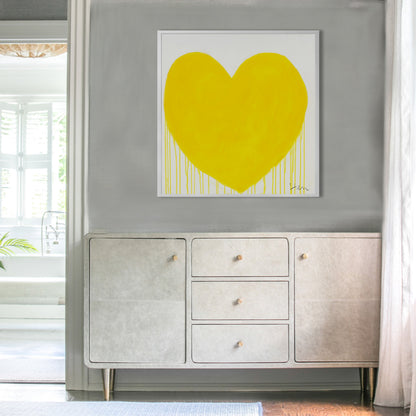 Kerri Rosenthal "You + Me + Whatever" art print: a large yellow drippy heart in a white frame, hanging above a light-colored console.