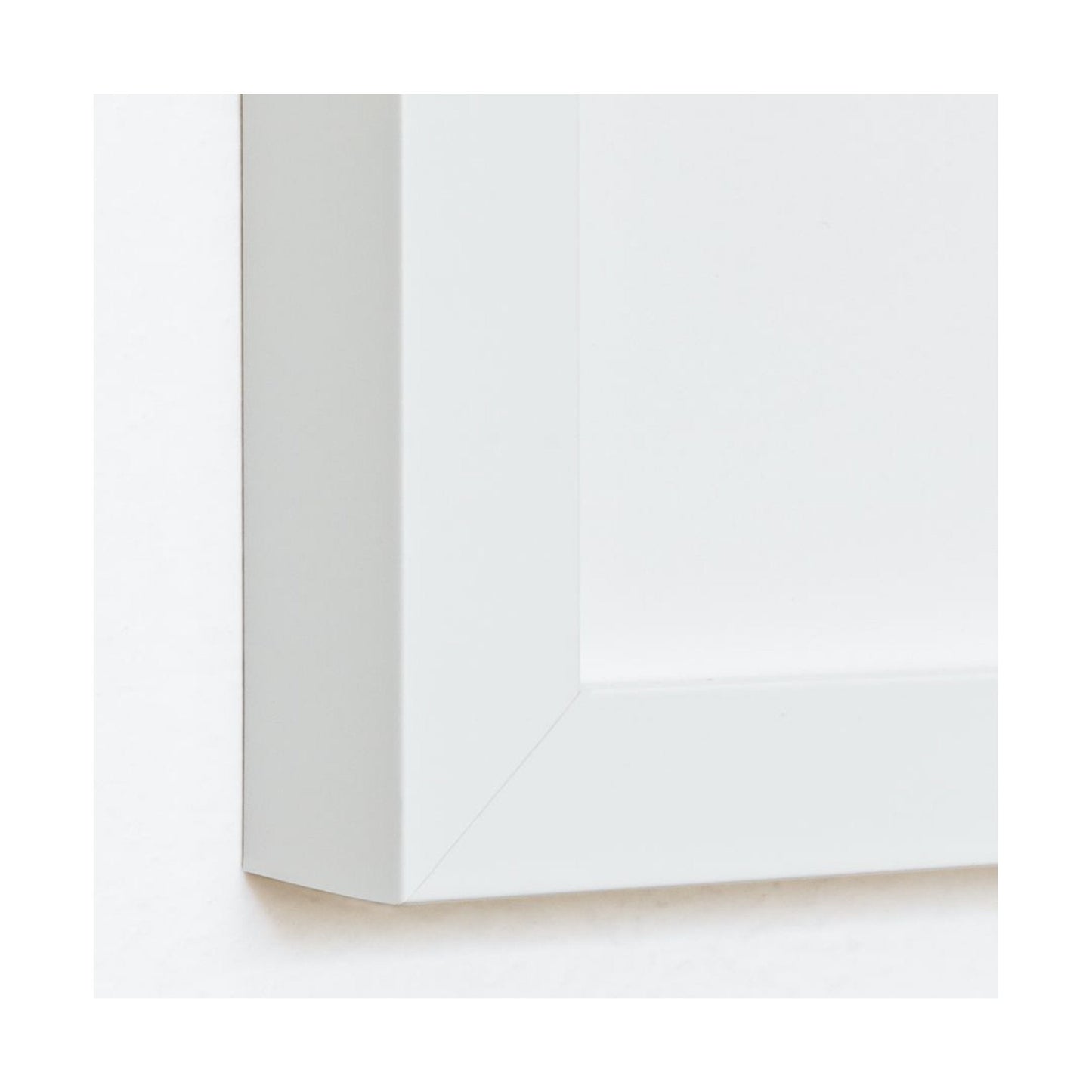 Close-up of a matte white wood art print frame, showing the mitered corner and profile.