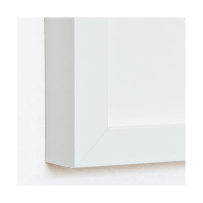 Close-up of a matte white wood art print frame, showing the mitered corner and profile.