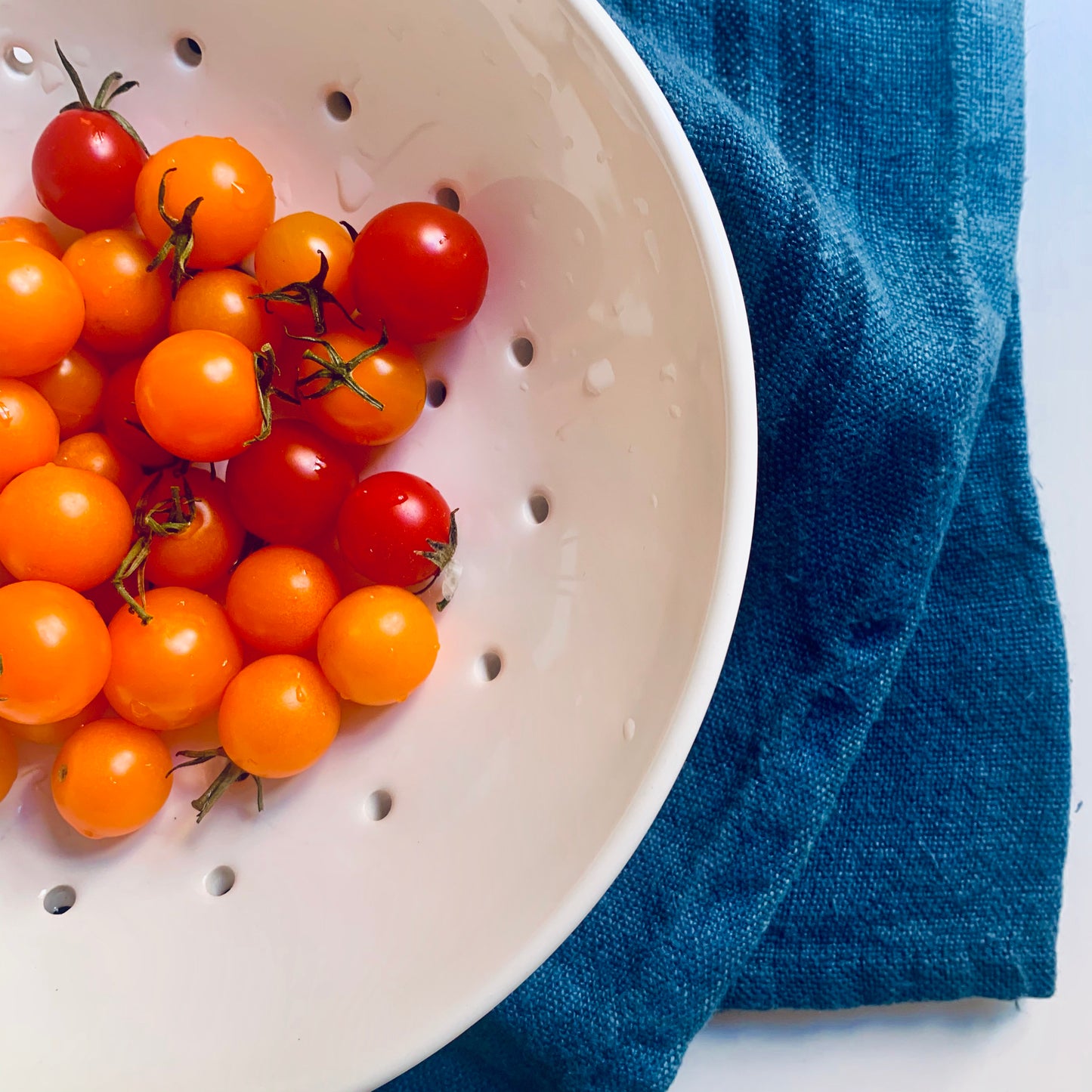 Hudson Grace White Ceramic Berry Bowl with cherry tomatoes and a blue towel