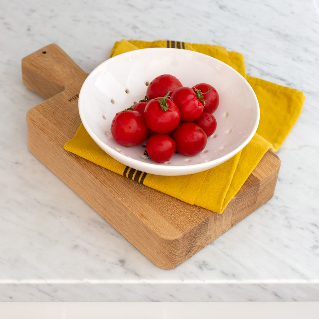 Hudson Grace White Ceramic Berry Bowl with tomatoes on yellow towel and wood serving board