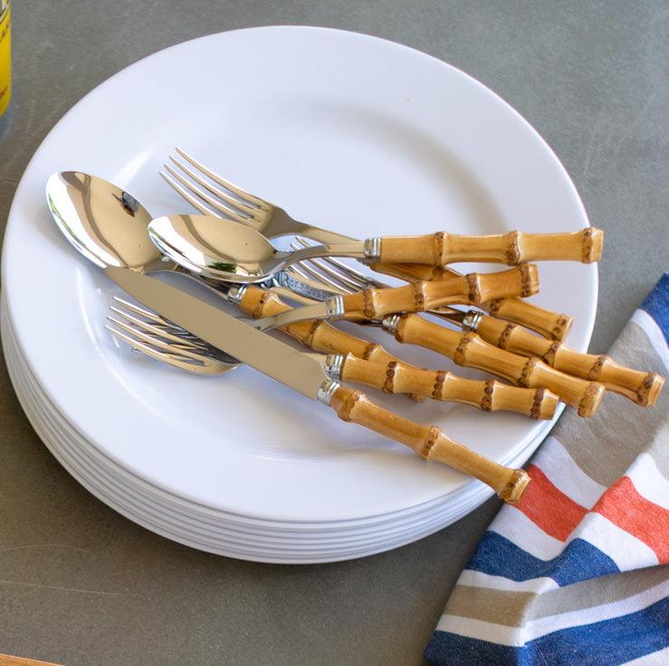 Bamboo 5-piece flatware set with 18/10 stainless steel and natural bamboo handles on white plates.
