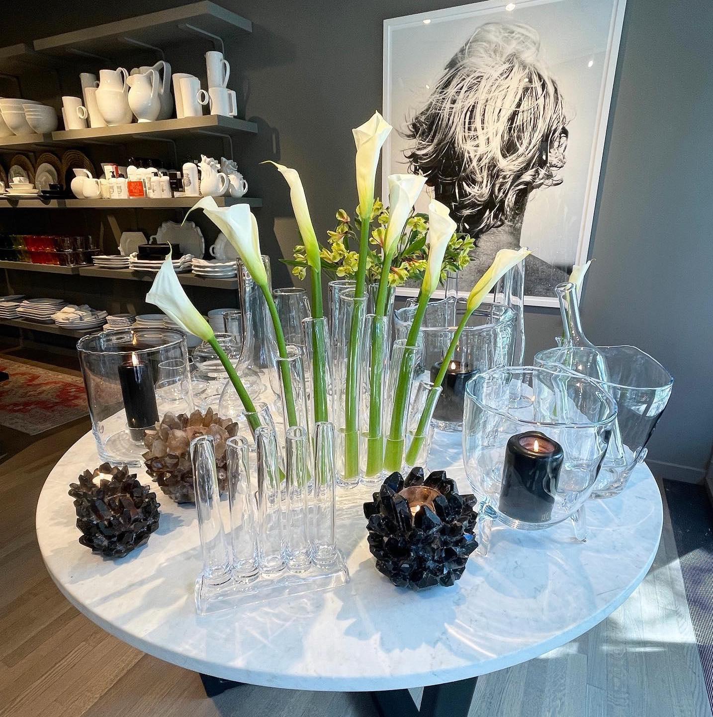 Black Grande Quartz Votive Candle Holder with raw quartz crystals, clear glass vases, and white calla lilies.