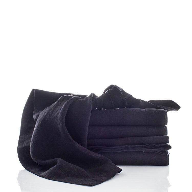 Stack of five folded Black HG Signature hand-dyed linen napkins, one draped loosely.