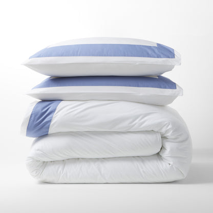 Stacked white percale pillow shams with blue wide bands and matching folded duvet.