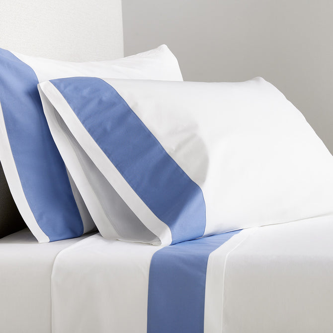 White percale sheet set with a bold blue wide-band detail on pillowcases and flat sheet.