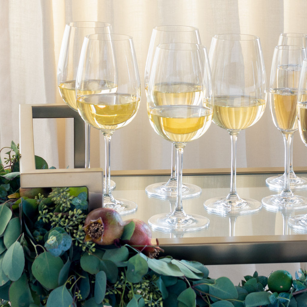 Brentwood Antique Brass Bar Cart with wine glasses, mirrored shelf, and decorative greenery.