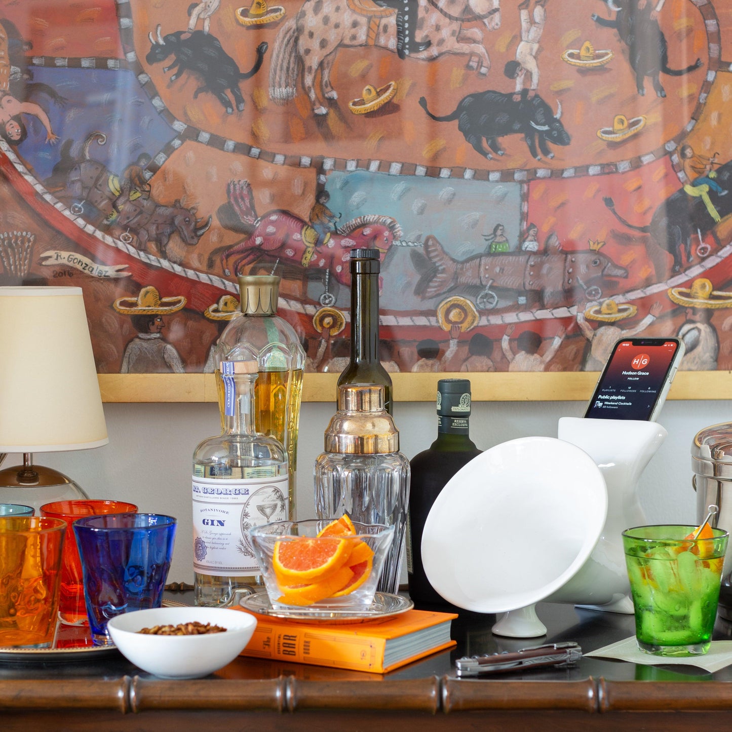 White ceramic kitchen speaker with a smartphone, surrounded by barware and drinks.