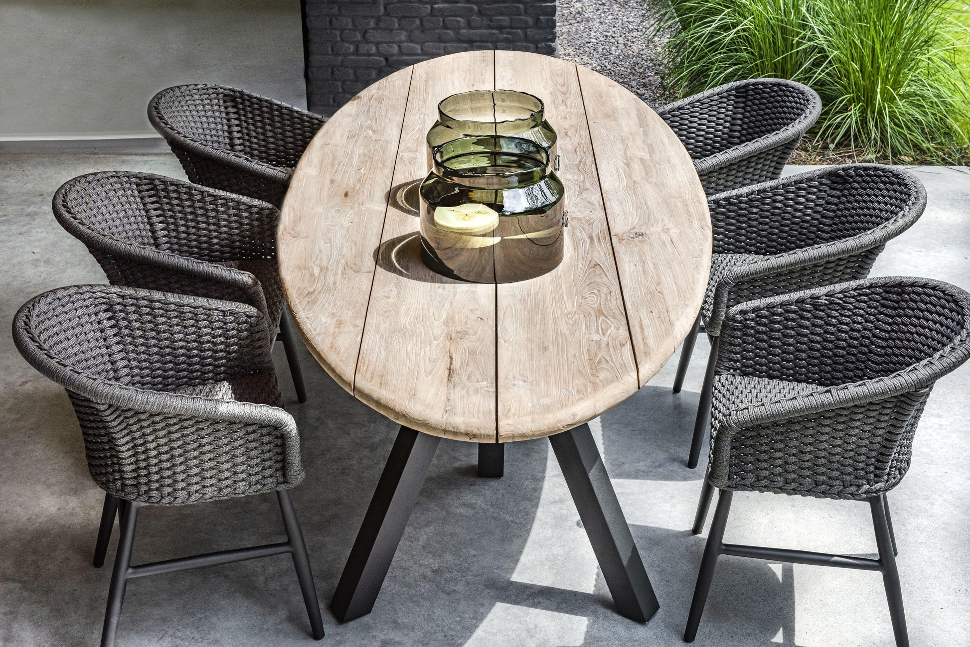 Charly Black Rope Dining Arm Chair with woven PE resin wicker and matte black aluminum frame, around a wood table.