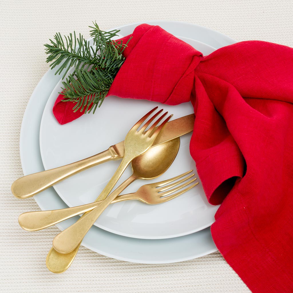HG Classic Porcelain Salad Plate, white, with gold flatware, red napkin, and pine sprig.