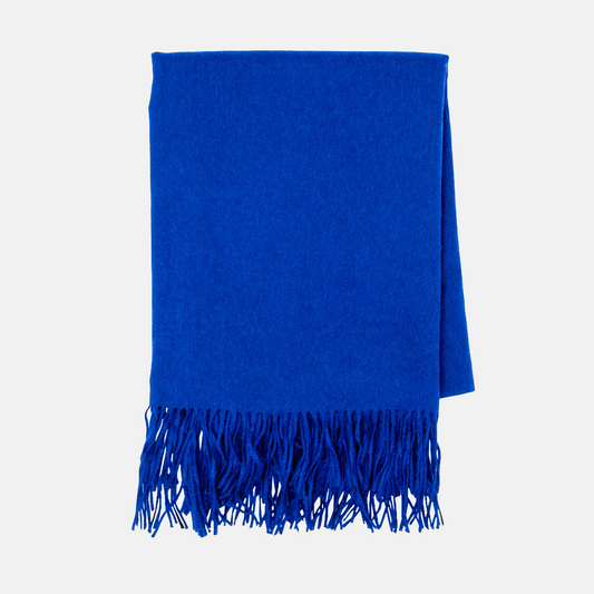 Cobalt blue cashmere throw blanket with classic fringe, folded.