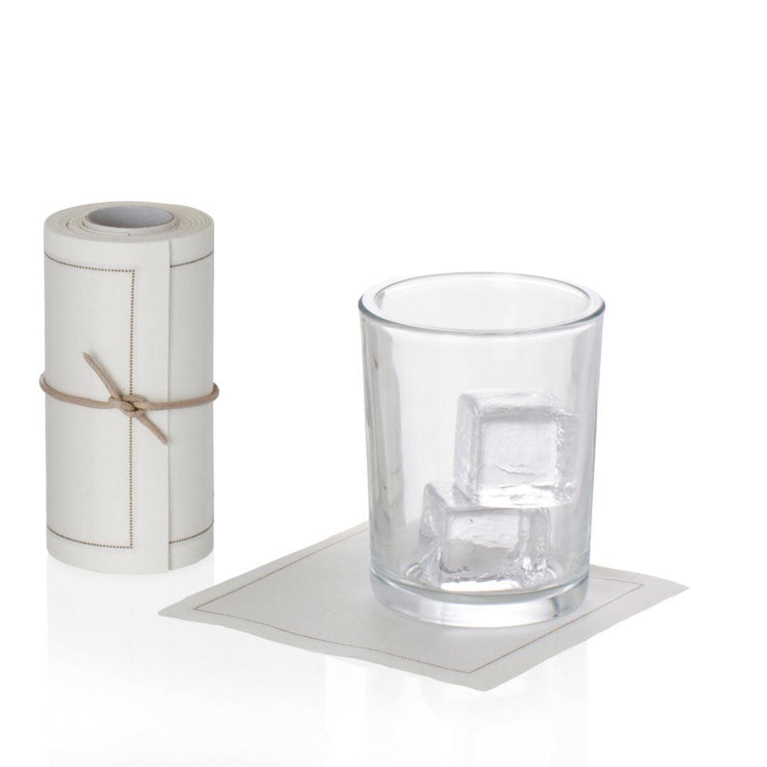 Cream tear-off cotton cocktail napkin roll with a single napkin under a glass with ice.