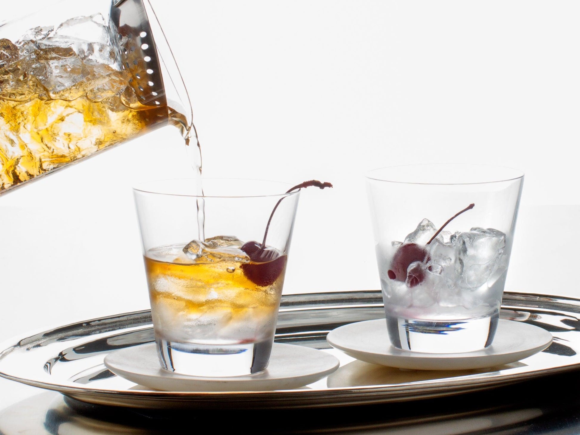Crystal whiskey glasses, set of 6, with ice and cherries on a silver tray.