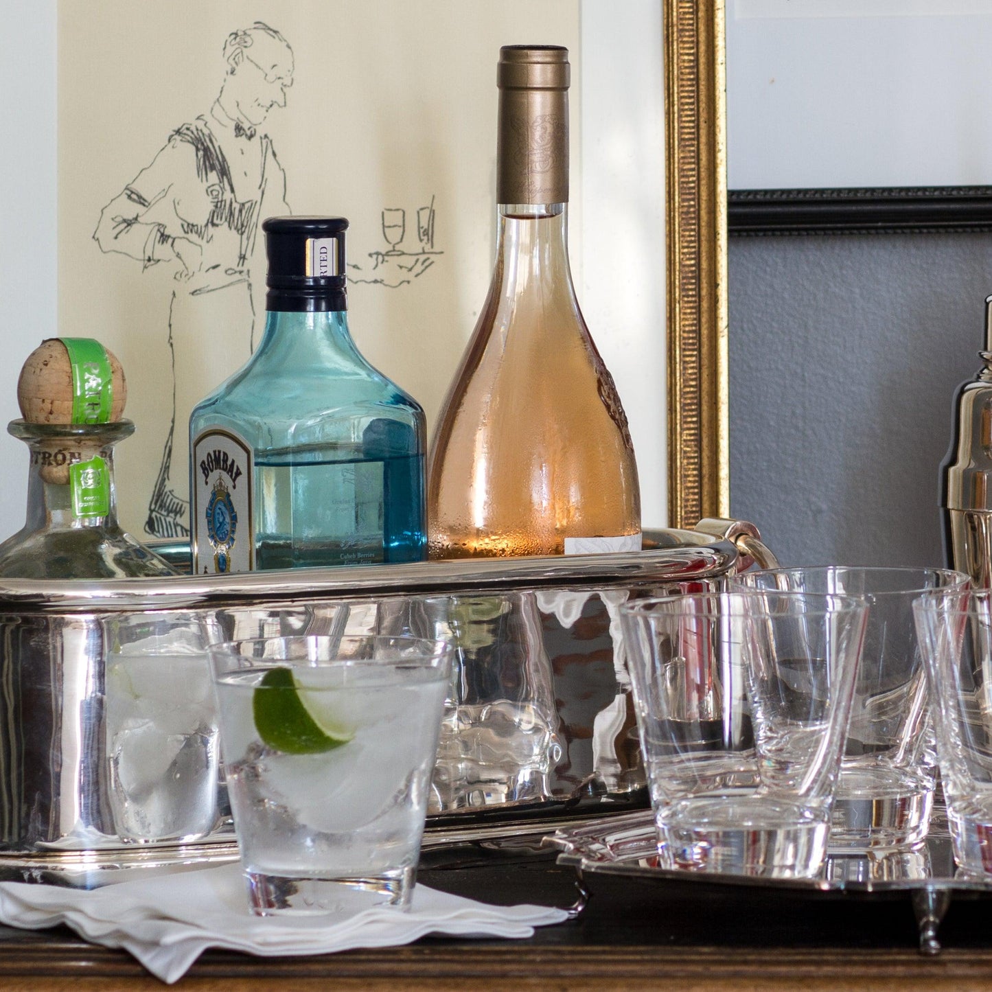 Set of 6 clear crystal whiskey glasses on a silver bar cart with liquor bottles.