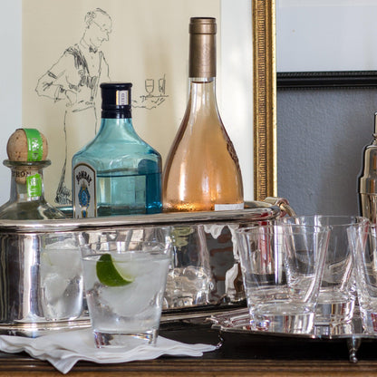 Set of 6 clear crystal whiskey glasses on a silver bar cart with liquor bottles.