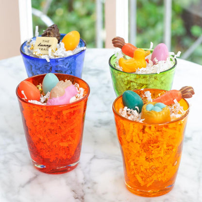 Four colorful Henri glasses filled with white shredded paper and Easter candies.