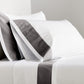White percale sheet set with dark grey wide-band detail on pillowcases and flat sheet.