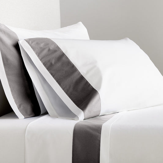 White percale sheet set with dark grey wide-band detail on pillowcases and flat sheet.