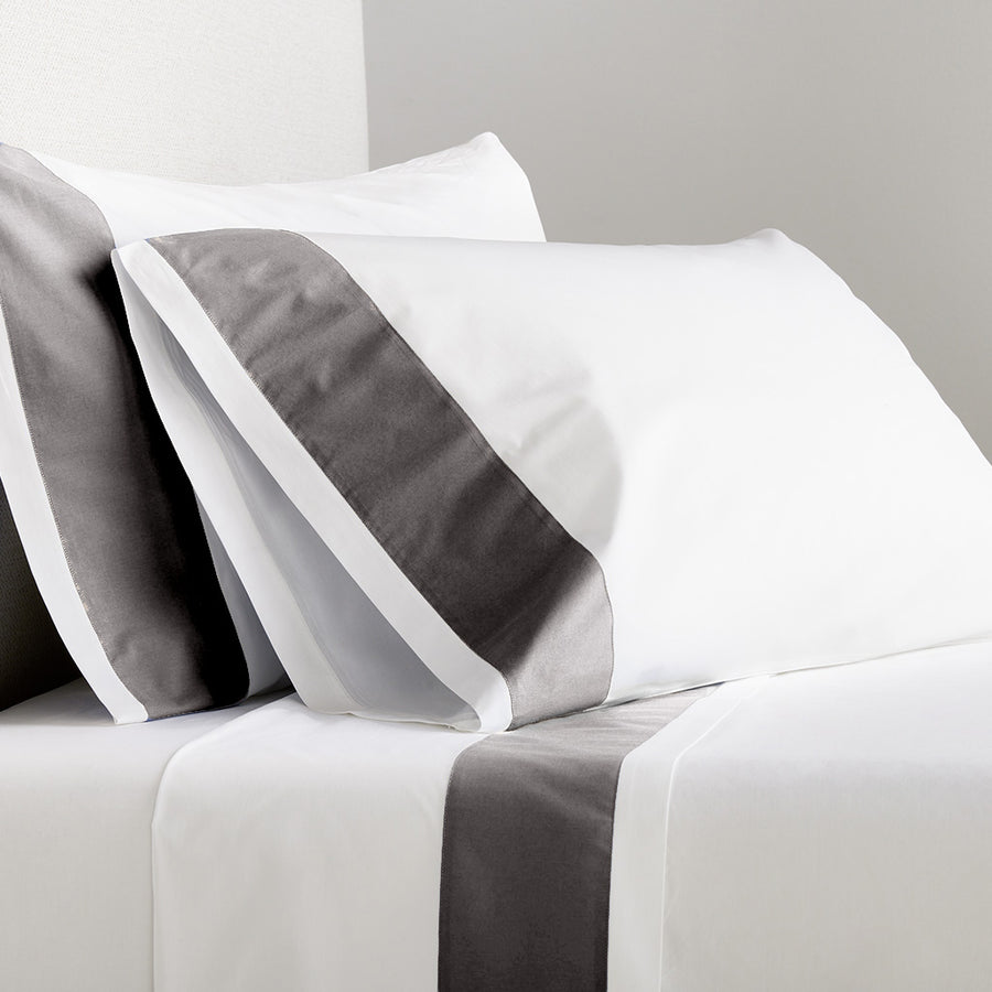 White percale sheet set with dark grey wide-band detail on pillowcases and flat sheet.