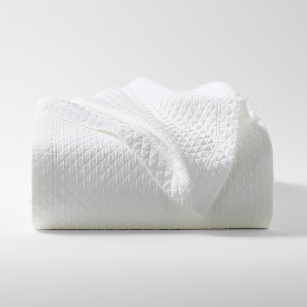 Diamond White Cotton Matelassé Coverlet, folded, showing subtle geometric pattern and rich texture.