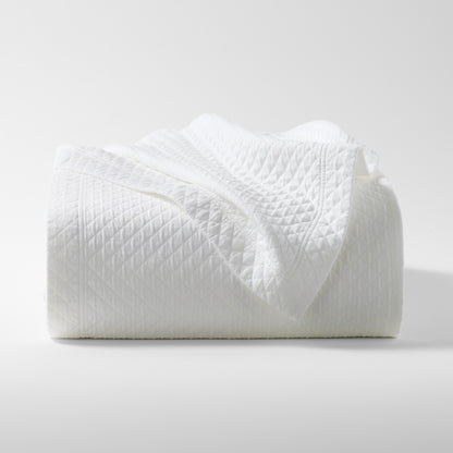Diamond White Cotton Matelassé Coverlet, folded, showing subtle geometric pattern and rich texture.