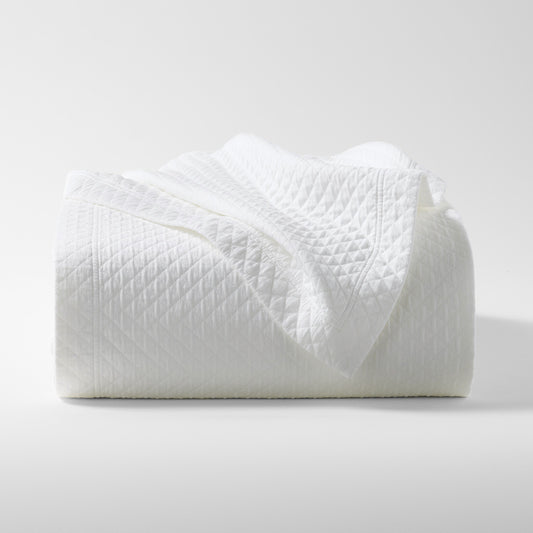 Diamond White Cotton Matelassé Coverlet, folded, showing subtle geometric pattern and rich texture.