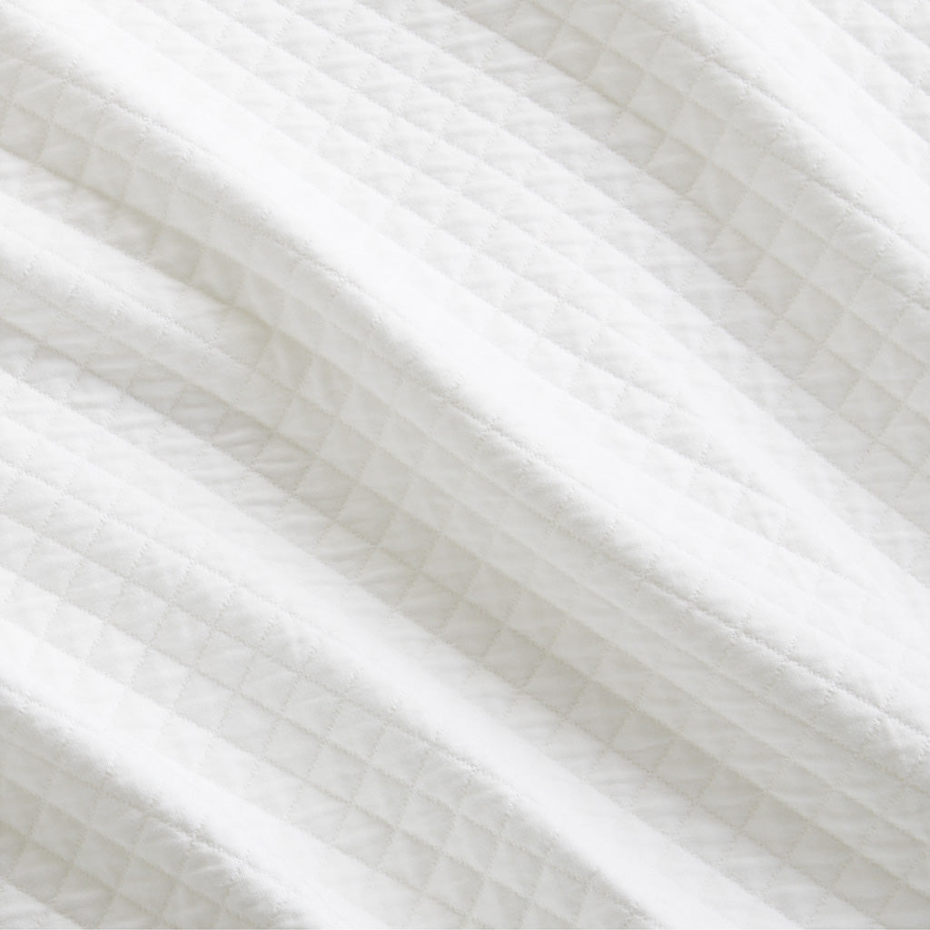 Close-up of a Diamond White Cotton Matelassé Pillow Sham with a subtle quilted diamond pattern.