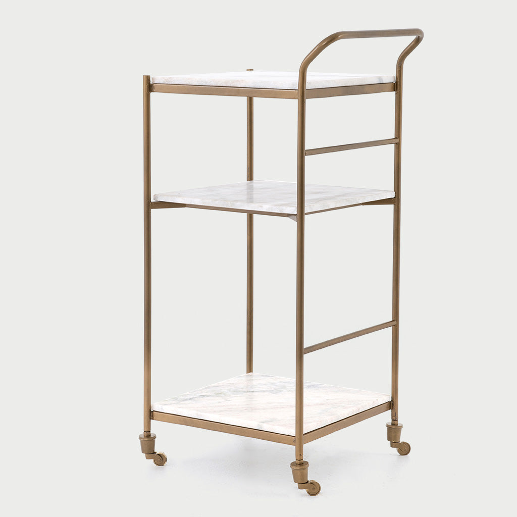 Felix antique brass bar cart with three square white marble shelves and casters.