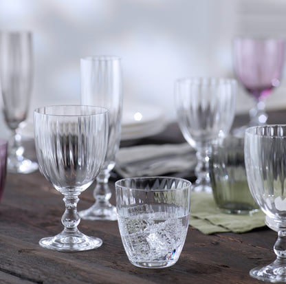Clear ribbed Eco-Crystal stemmed wine glass, 12oz, with other glassware on a wooden table.