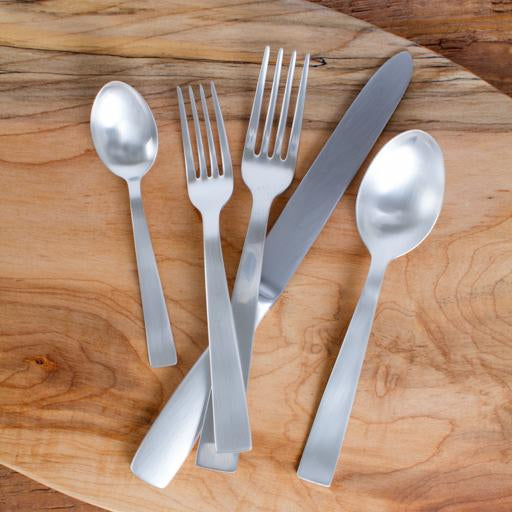 Gio Ponti 5-piece satin silverplate flatware set: table fork, knife, dessert fork, dessert spoon, teaspoon on wood.