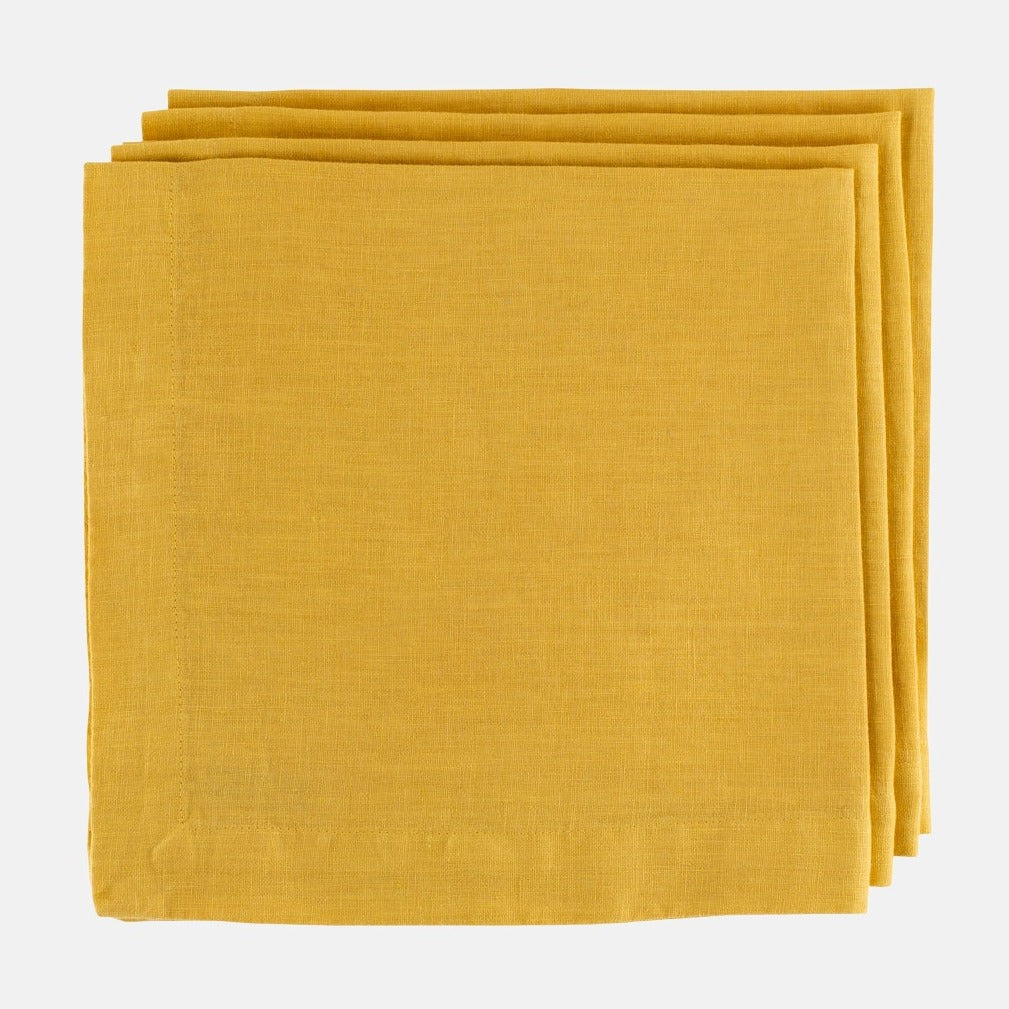Stack of Golden Mustard HG Signature hand-dyed 22-inch linen napkins with mitered corners.