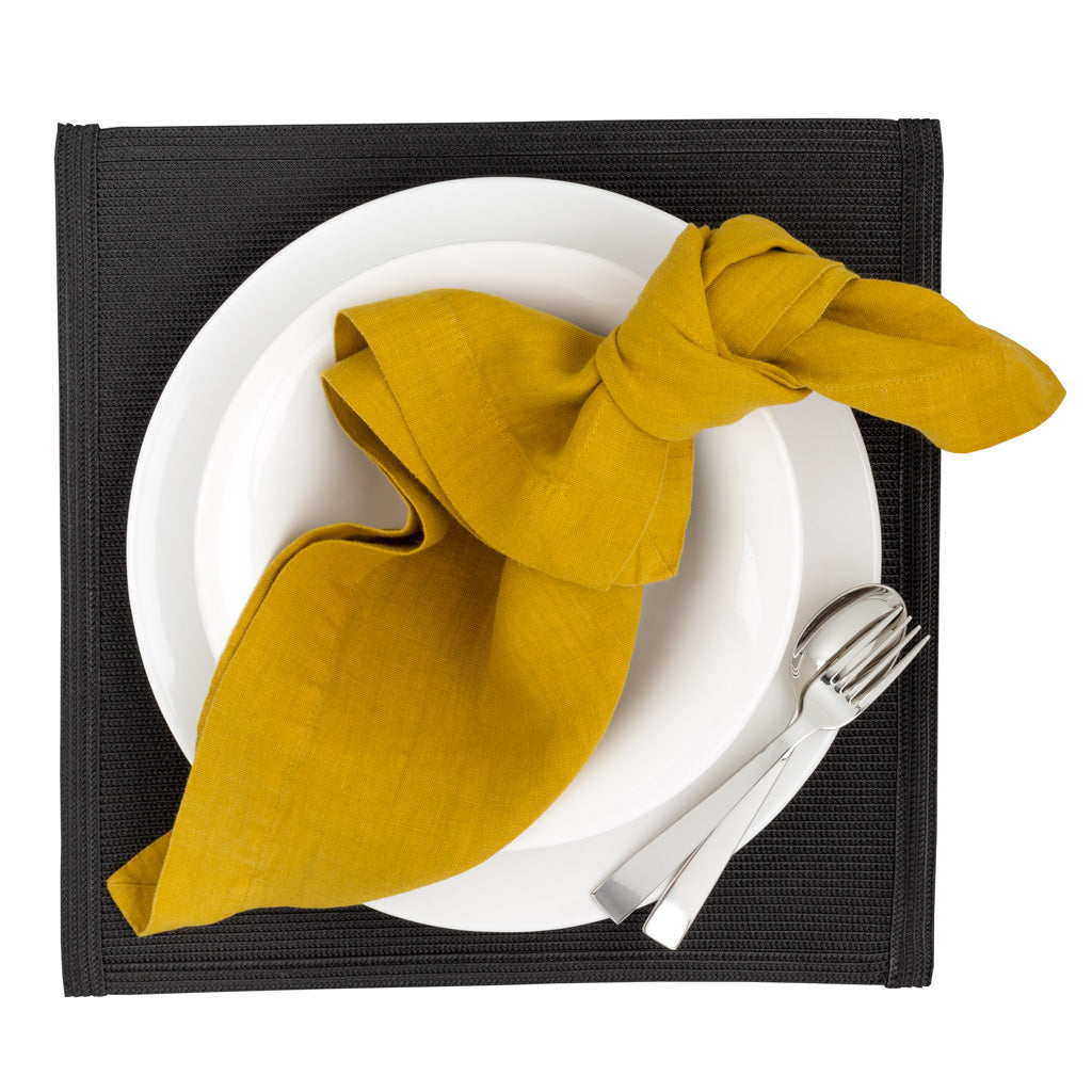Golden Mustard HG Signature hand-dyed linen napkin, knotted on a white plate with silverware.