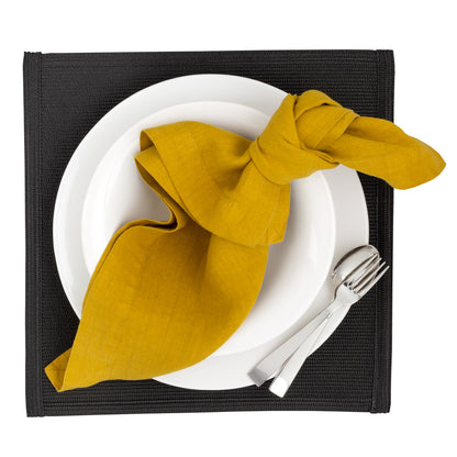 Golden Mustard HG Signature hand-dyed linen napkin, knotted on a white plate with silverware.
