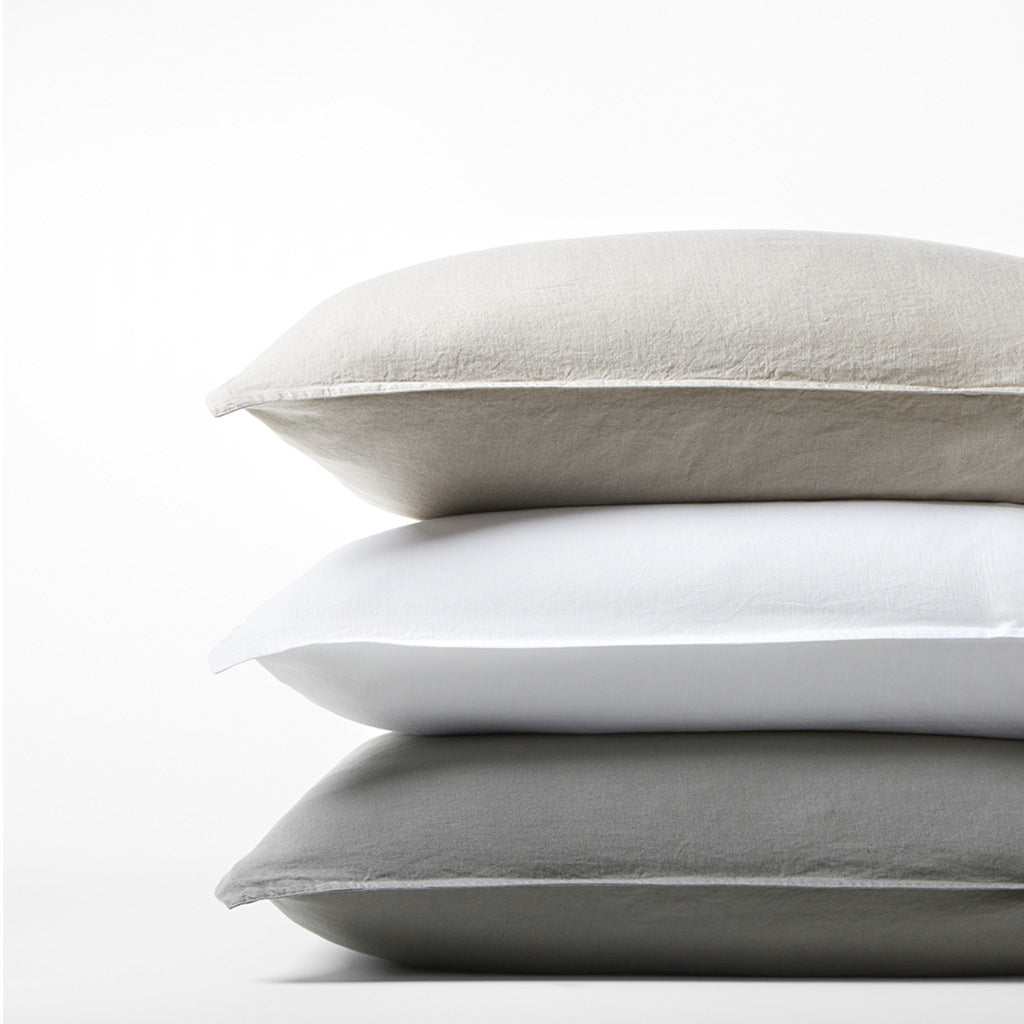 Stack of three Washed-Linen Pillow Shams: light grey, white, and dark grey.