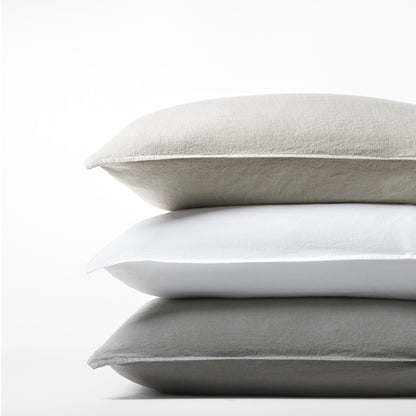 Stack of three Washed-Linen Pillow Shams: light grey, white, and dark grey.