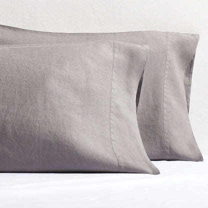 Two grey washed-linen pillowcases with double-needle stitch detailing, resting on a white sheet.