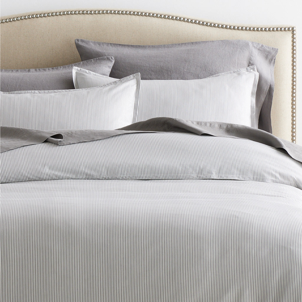 Grey Stripe Cotton-Chambray Duvet Cover with thin vertical stripes and matching shams on a bed.