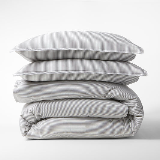 Stacked Grey Stripe Cotton-Chambray Duvet Cover and two pillow shams with thin stripes.