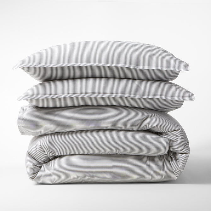 Stacked Grey Stripe Cotton-Chambray Duvet Cover and two pillow shams with thin stripes.
