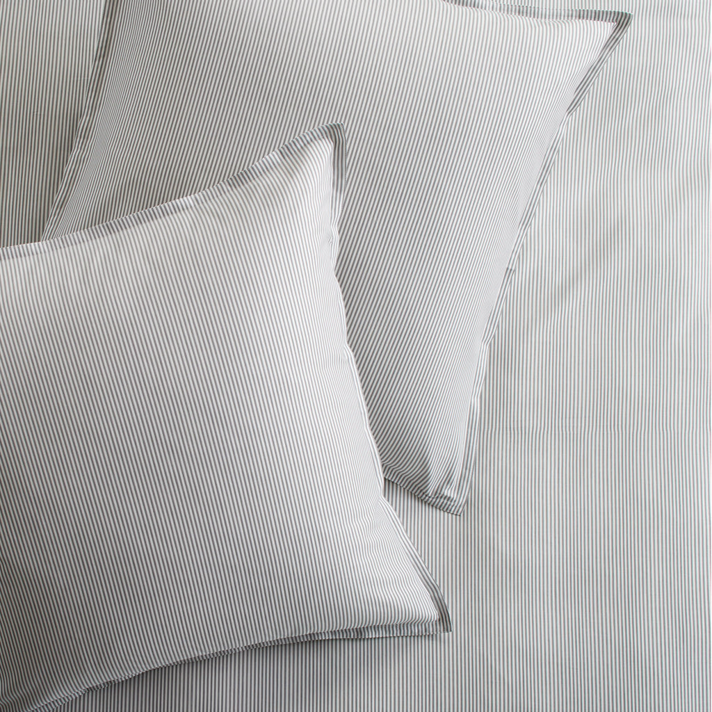 Set of 2 grey stripe cotton-chambray pillow shams with 2” flange and double-needle stitching.