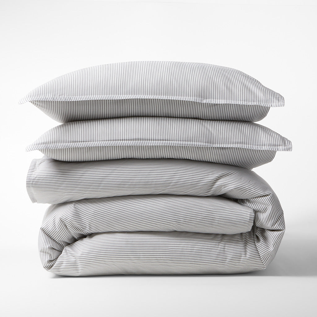 Stacked grey stripe cotton-chambray pillow shams and folded duvet cover.