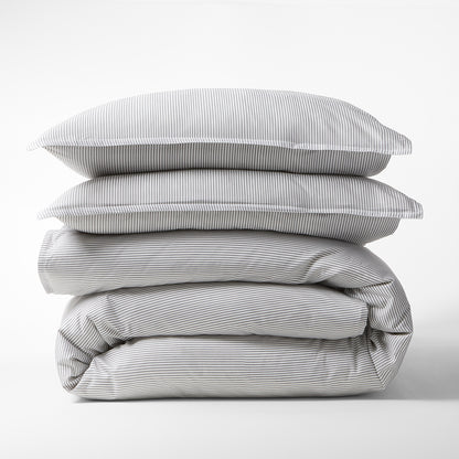 Stacked grey stripe cotton-chambray pillow shams and folded duvet cover.