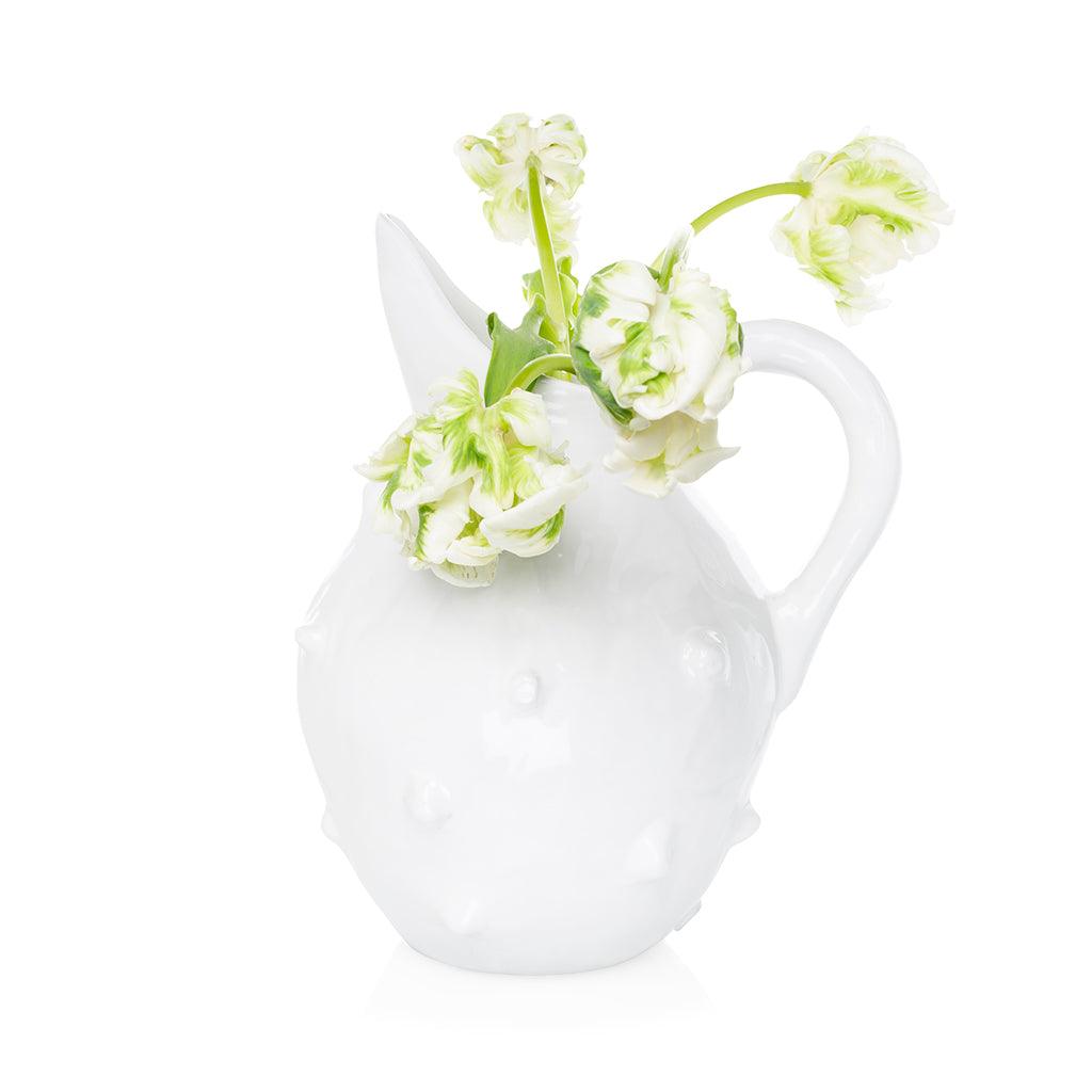 Handmade creamy white ceramic bumpy pitcher by Montes Doggett with green and white flowers.