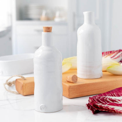 Handmade creamy white ceramic oil and vinegar cruets with cork stoppers on a wooden tray.