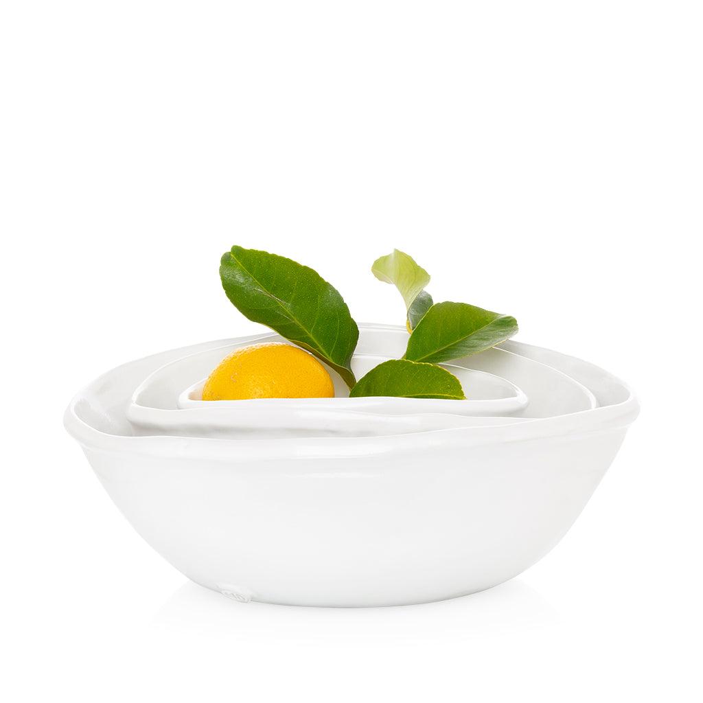 Set of 3 Montes Doggett handmade white ceramic oval bowls, nested with a lemon and green leaves.
