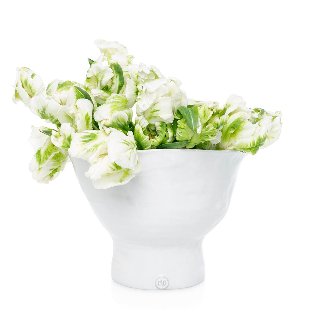 Handmade creamy white ceramic pedestal bowl by Montes Doggett, filled with green and white tulips.