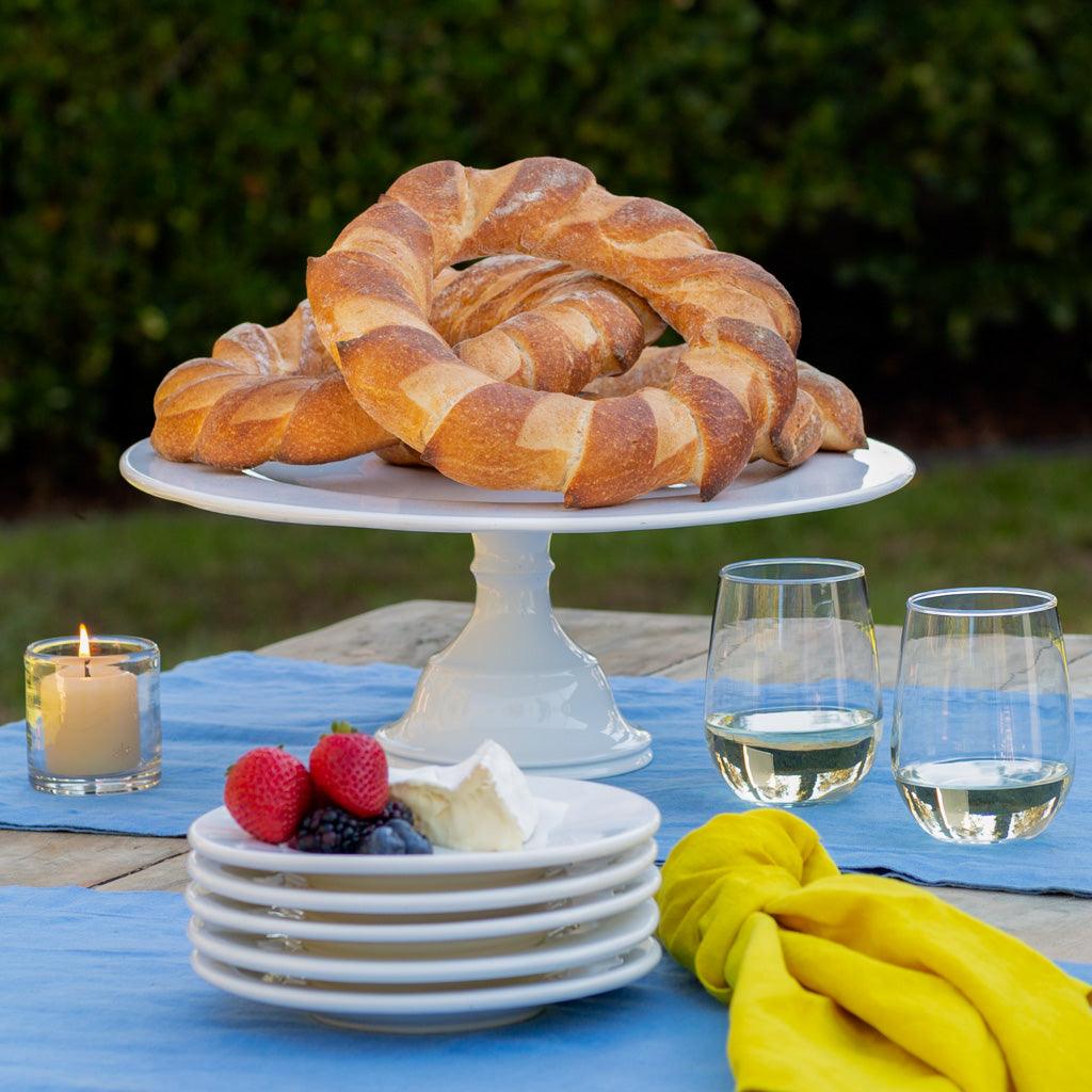 HG Original Large Pedestal Cake Stand, creamy white ceramic, holding braided bread.